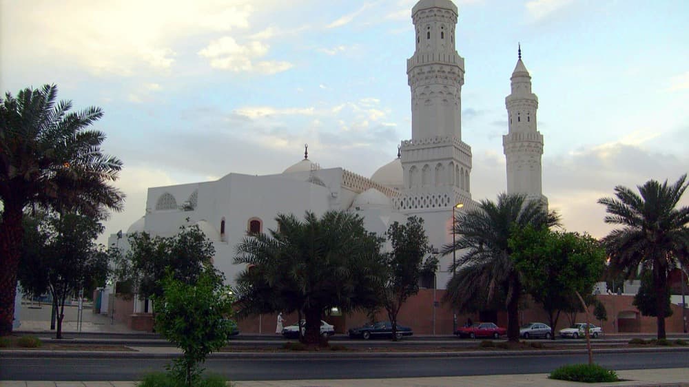 The exterior of Masjid al-Qiblatayn, the masjid of the two qiblahs, framed by palm trees.